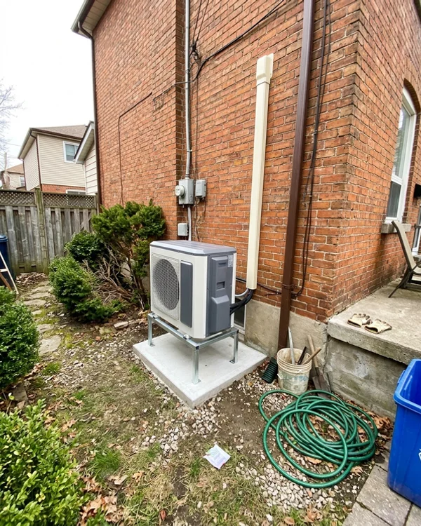 New cold-climate heat pump outdoor unit on a raised pad after installation
