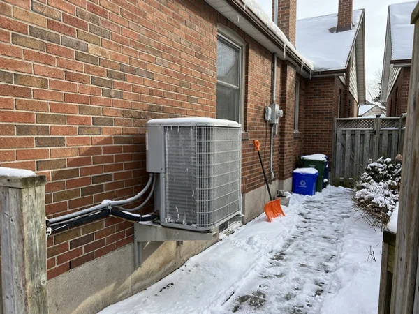 Heat pump running in January snow beside a Toronto home