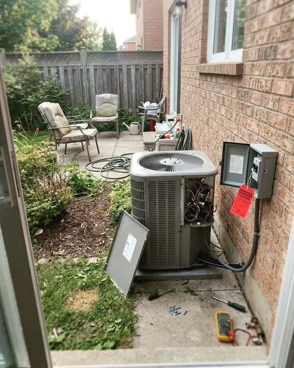 Outdoor unit with the panel off and a tripped breaker tag before repair