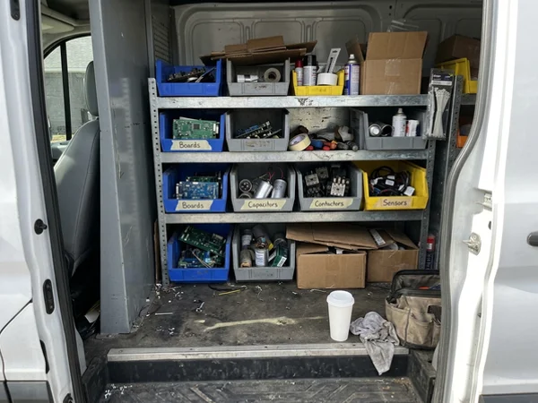 Service van shelving stocked with heat pump boards, capacitors and sensors